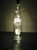 A close-up of a glowing bottle with an intricate floral design sitting on a rustic wooden table.