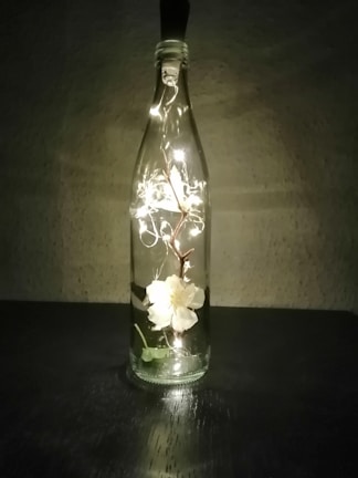 A close-up of a glowing bottle with an intricate floral design sitting on a rustic wooden table.