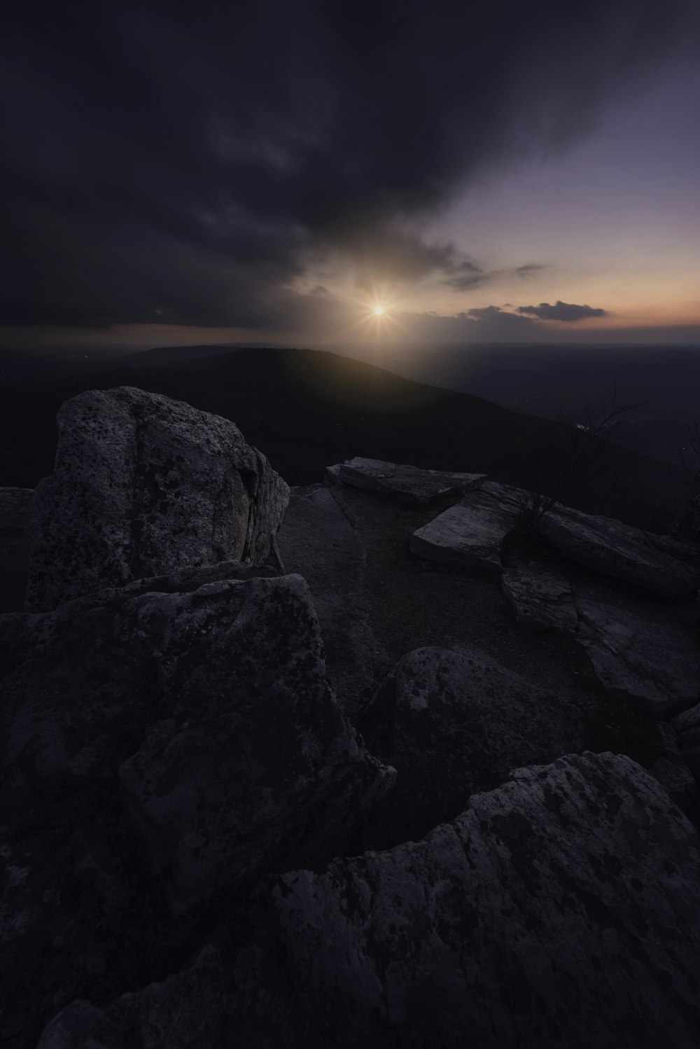 the sun is setting over a rocky outcropping