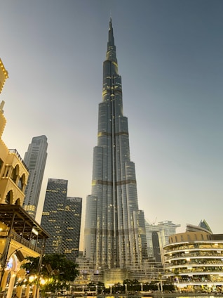 A sleek modern skyscraper rising above a vibrant urban landscape at sunset, symbolizing strategic real estate development.