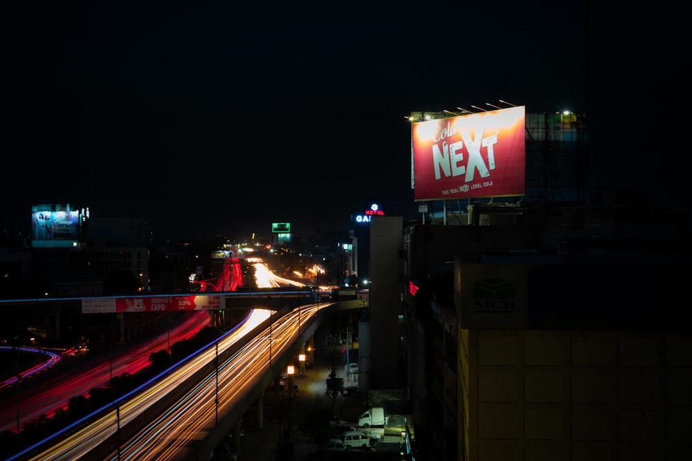 a city street at night with a neon exit sign