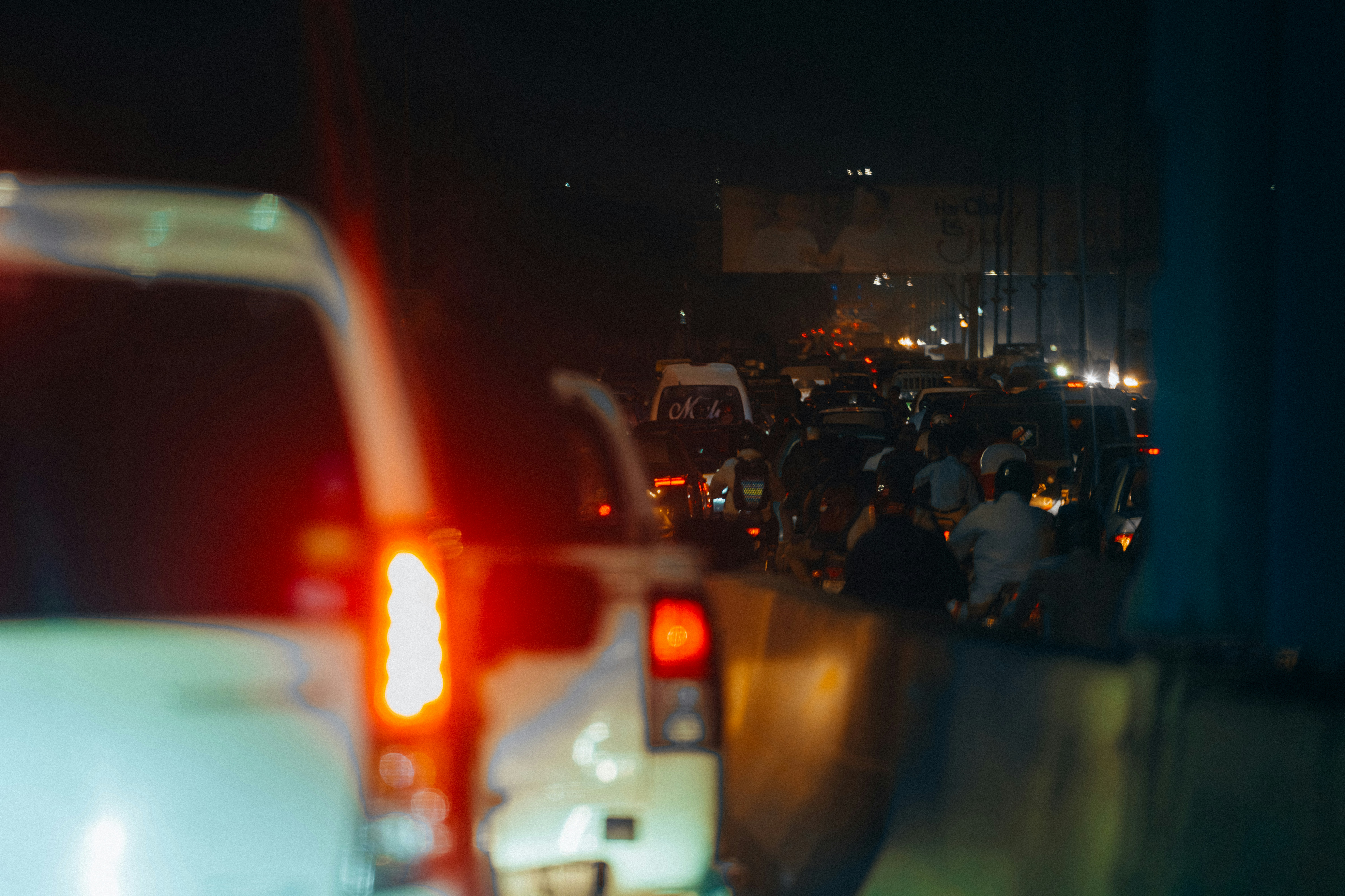 A heavy traffic jam at night, the road illuminated by the brake lights of cars disppearing into the horizon.