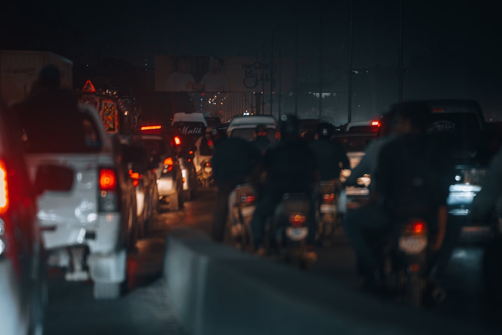 a group of people riding motorcycles down a street at night