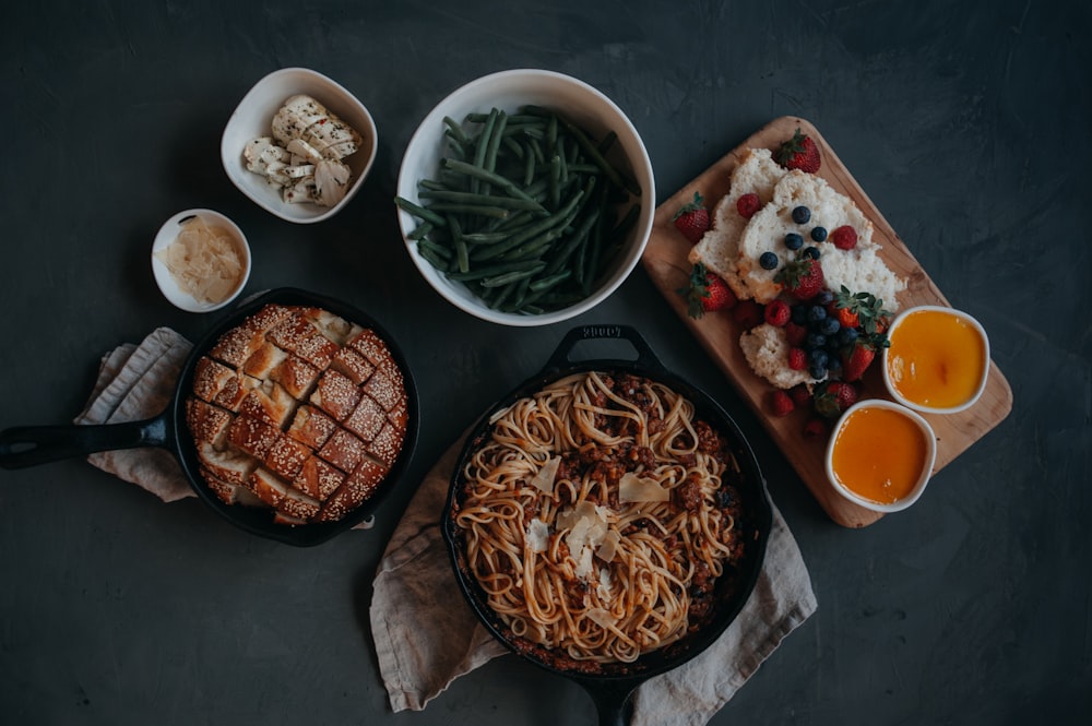 a table topped with plates of food and bowls of fruit