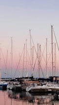 A serene marina at sunset with sailboats gently rocking on the water.