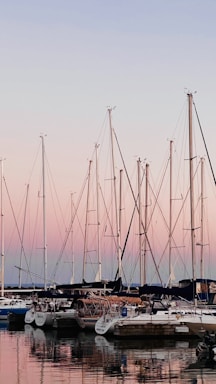 A serene marina at sunset with sailboats gently rocking on the water.