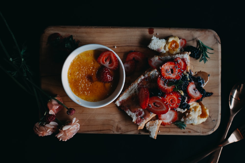 a wooden cutting board topped with a bowl of soup