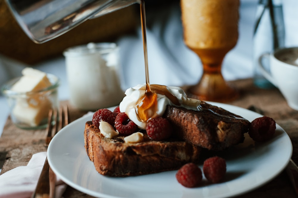 a plate of french toast topped with whipped cream and raspberries