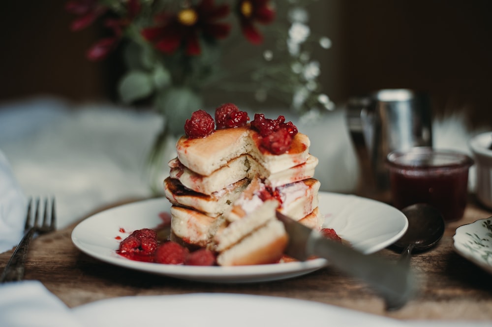 a stack of pancakes with raspberries on a plate