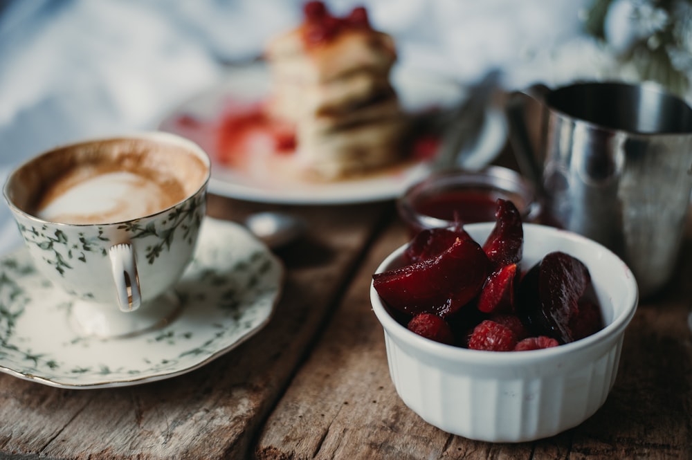 a cup of coffee and a plate of strawberries on a table