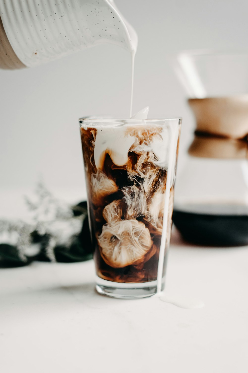 a person pouring milk into a glass filled with ice