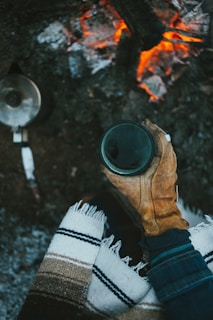 Earl bundled up in a flannel shirt, holding a steaming mug beside a space heater.