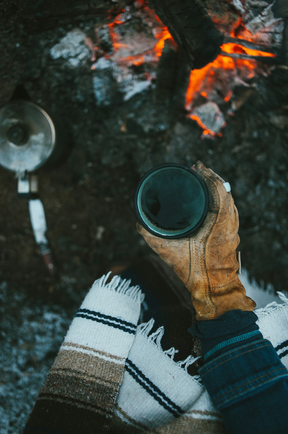 a person's feet in a pair of boots next to a campfire