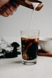 Fresh milk being poured into a glass on a rustic wooden table.
