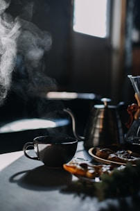A steaming cup of specialty coffee next to a pastry on a cozy café table.