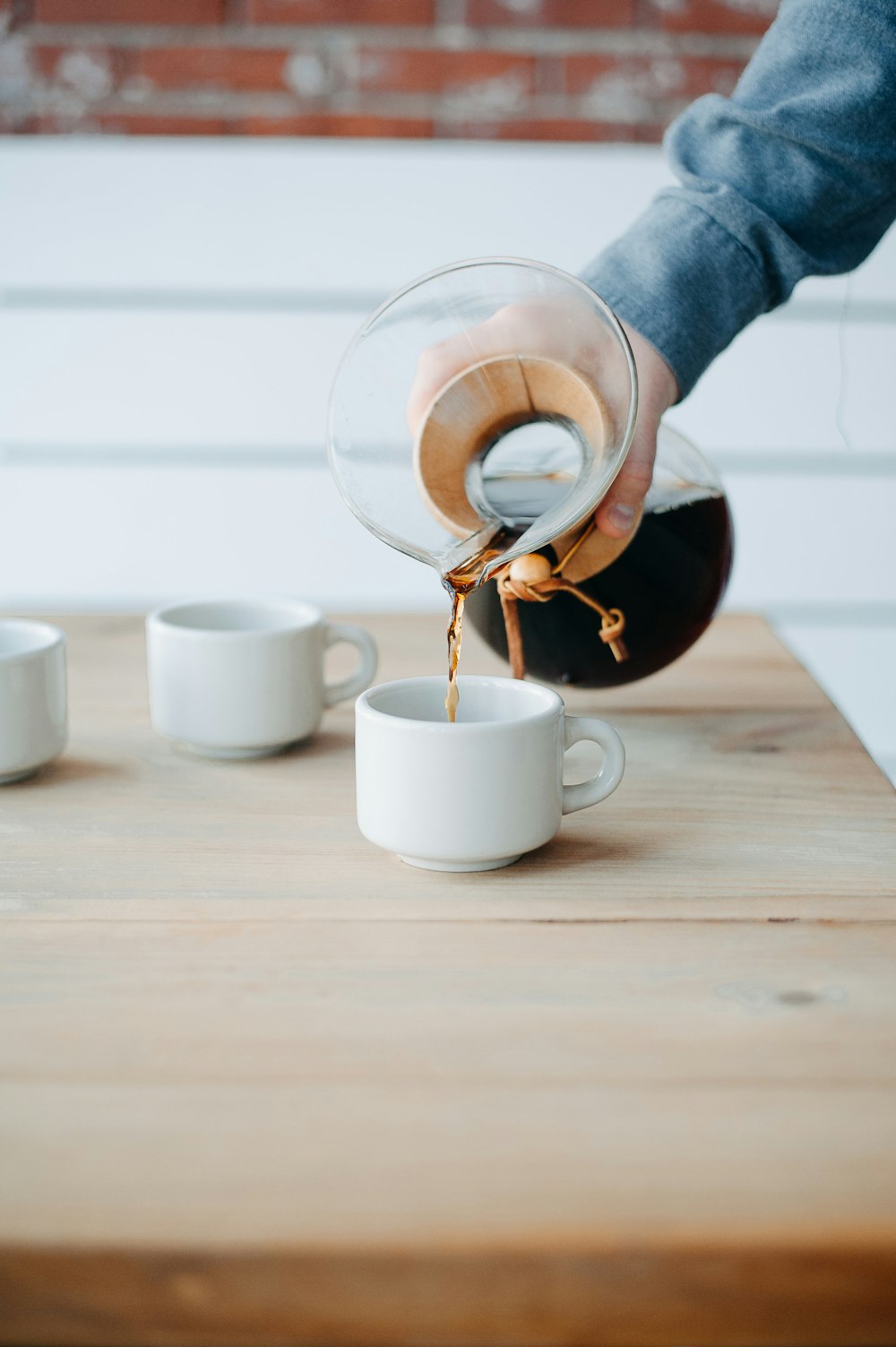 a person pours a cup of coffee from a pitcher