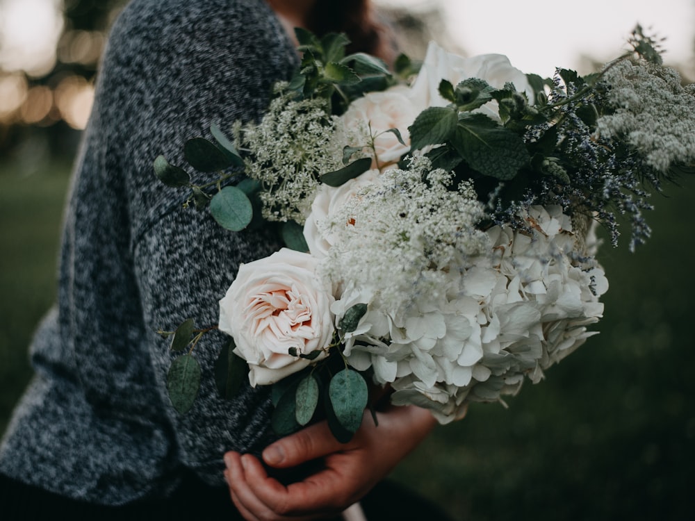 a woman holding a bouquet of white flowers