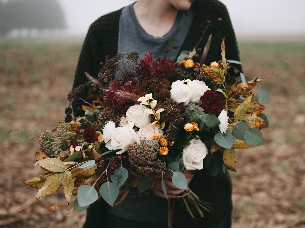 a woman holding a bouquet of flowers in a field