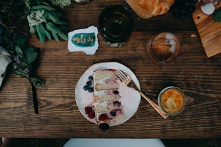 A rustic wooden table with a handwritten note and a pen beside a plate of colorful healthy cakes.