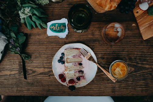 A rustic wooden table with a handwritten note and a pen beside a plate of colorful healthy cakes.
