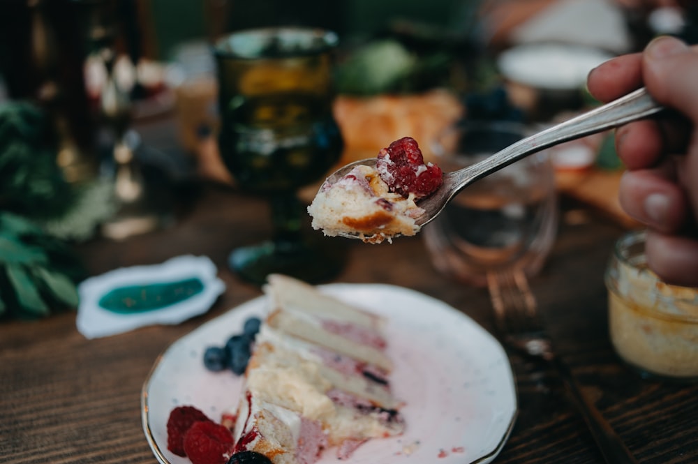 a person holding a fork with a piece of cake on it