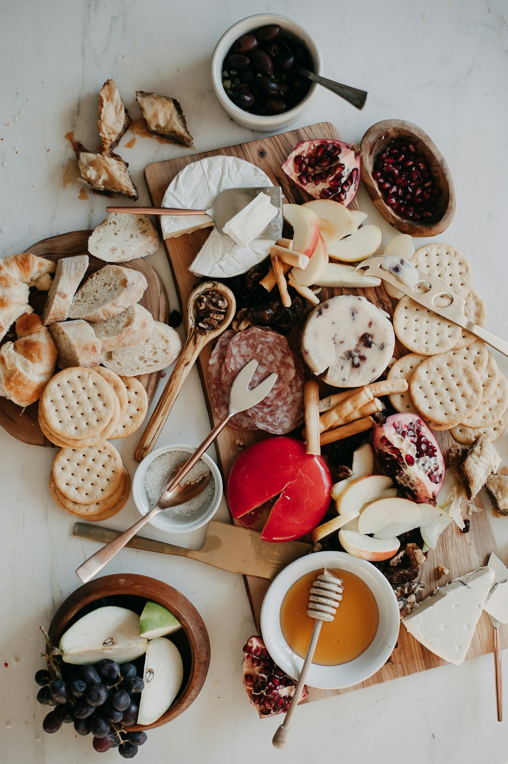 a variety of cheeses, crackers, and fruit on a cutting board