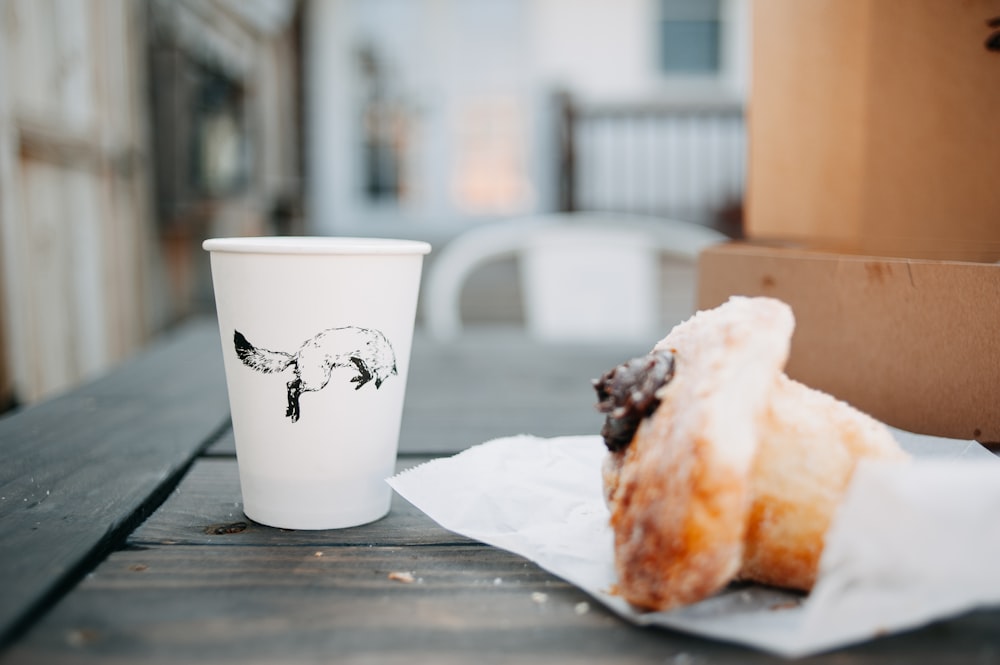 a half eaten doughnut next to a cup of coffee
