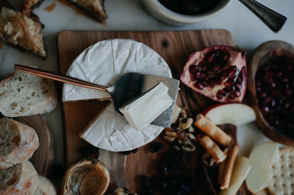 Artful display of twelve different fondue varieties served with traditional accompaniments on a wooden board.