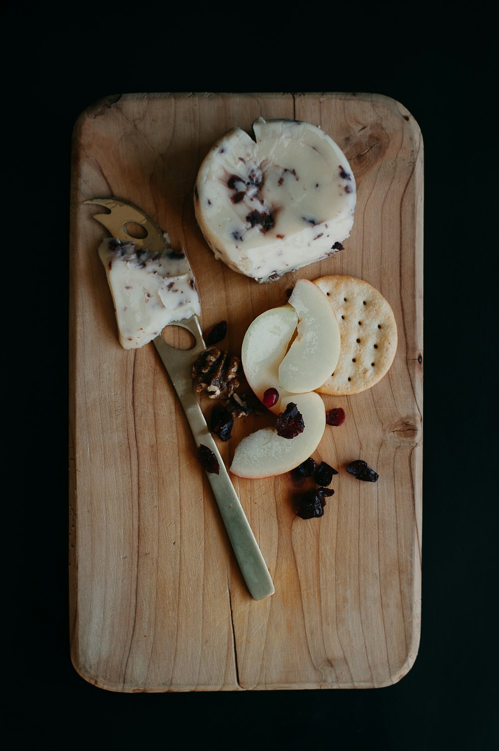 a wooden cutting board topped with cheese and crackers