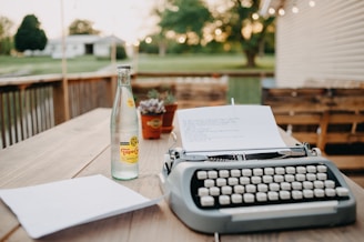 a bottle of beer and a typewriter on a table