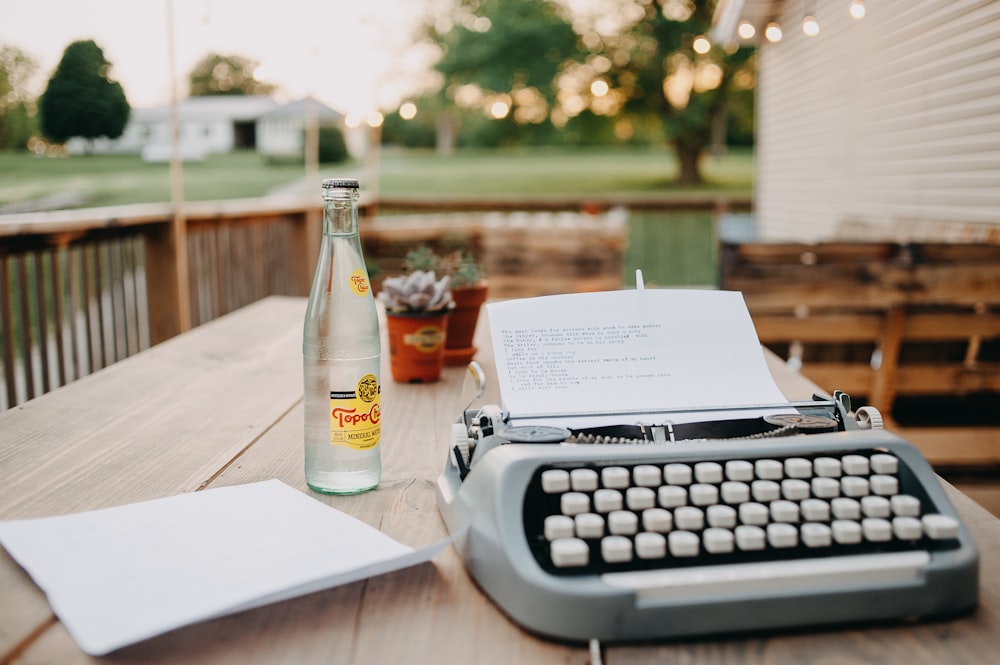 a bottle of beer and a typewriter on a table