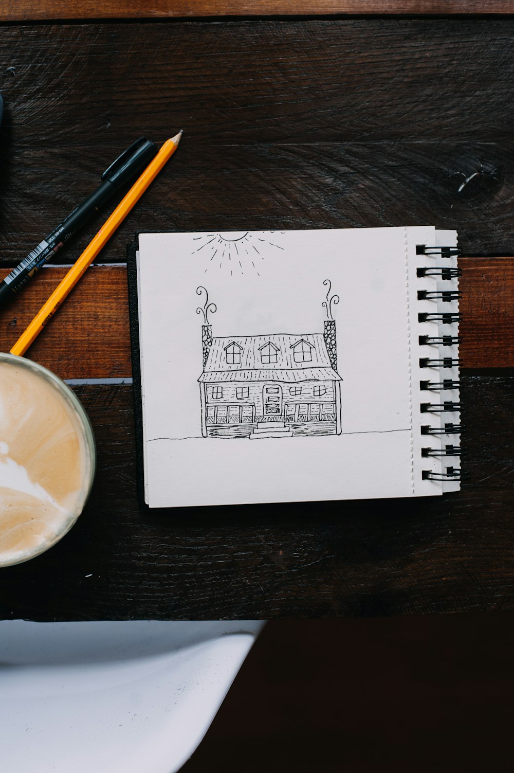 a drawing of a house next to a cup of coffee