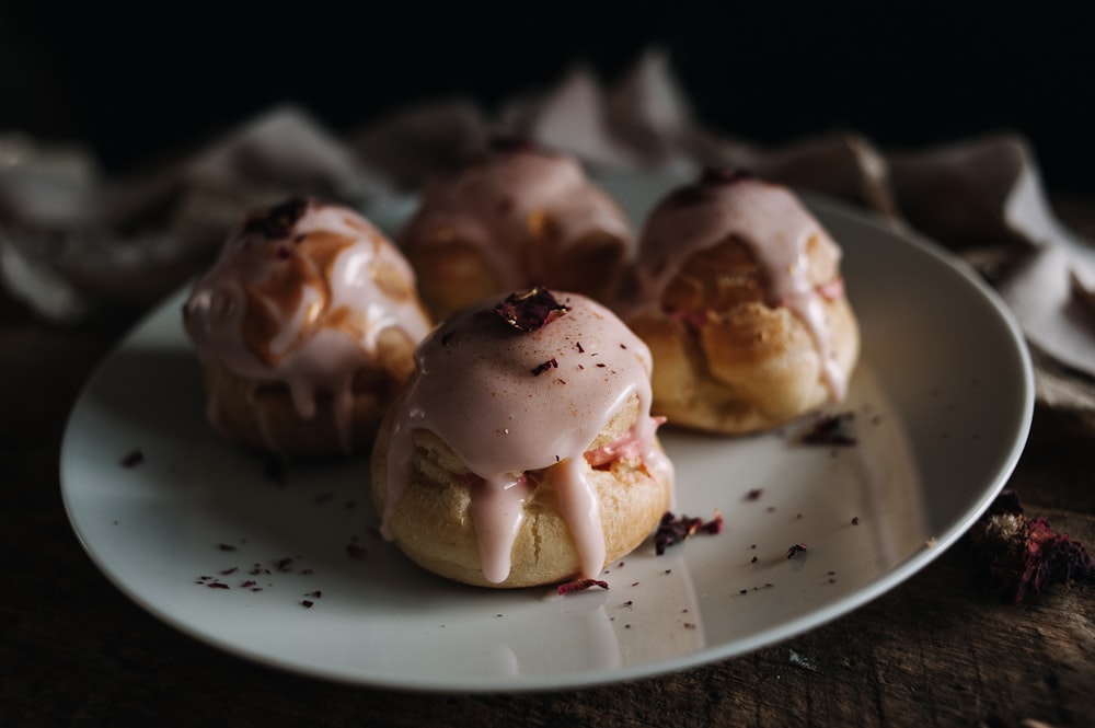 a white plate topped with pastries covered in icing