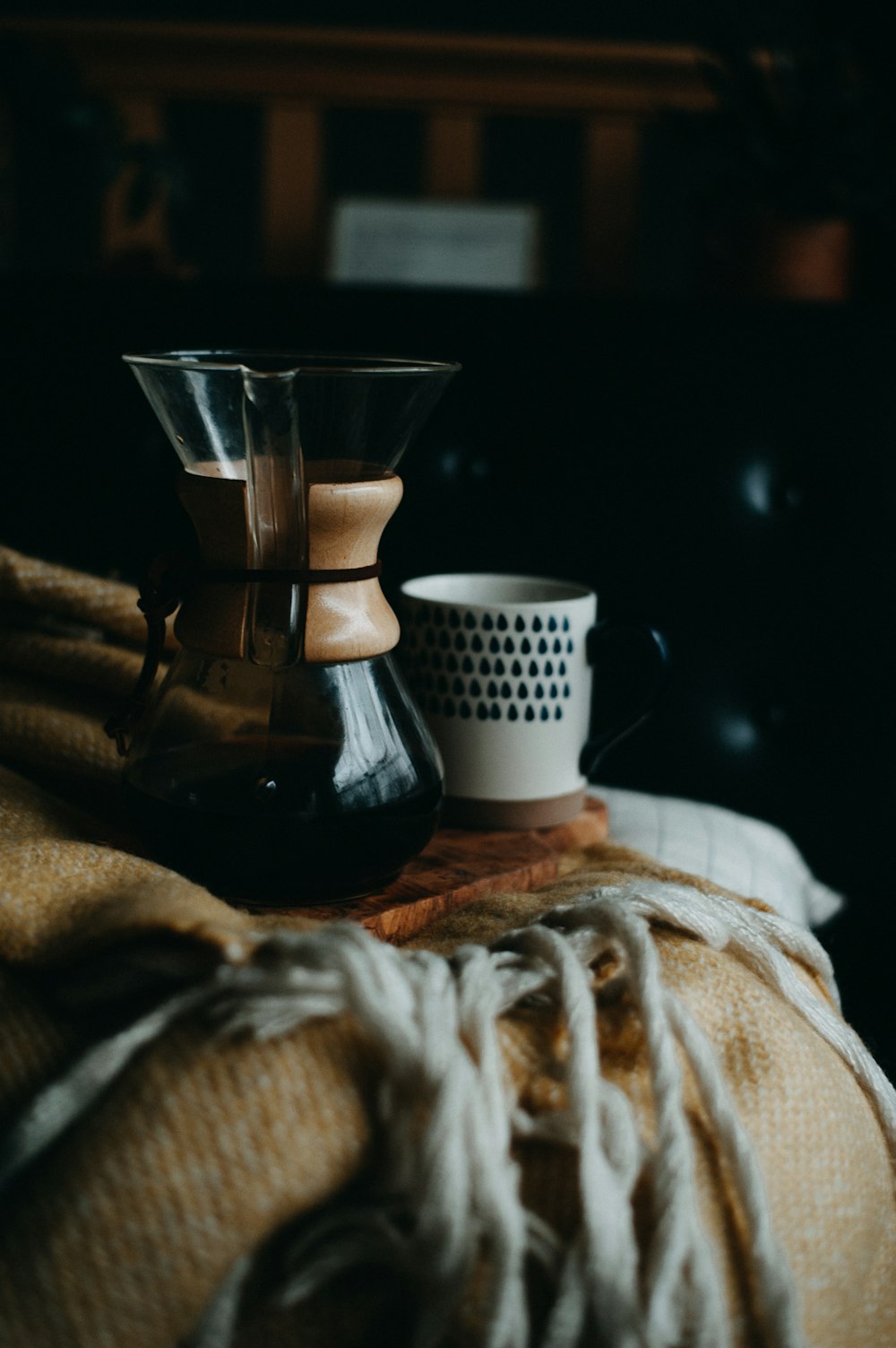 a coffee pot sitting on top of a bed next to a cup