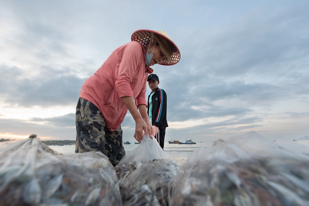 a woman in a pink shirt is picking up plastic bags