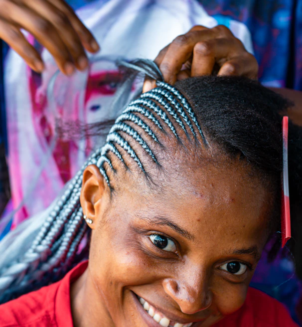 A client smiling with freshly done box braids styled with golden cuffs