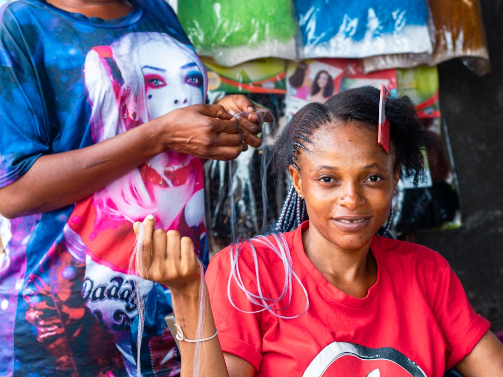 a woman getting her hair cut by a woman in a red shirt