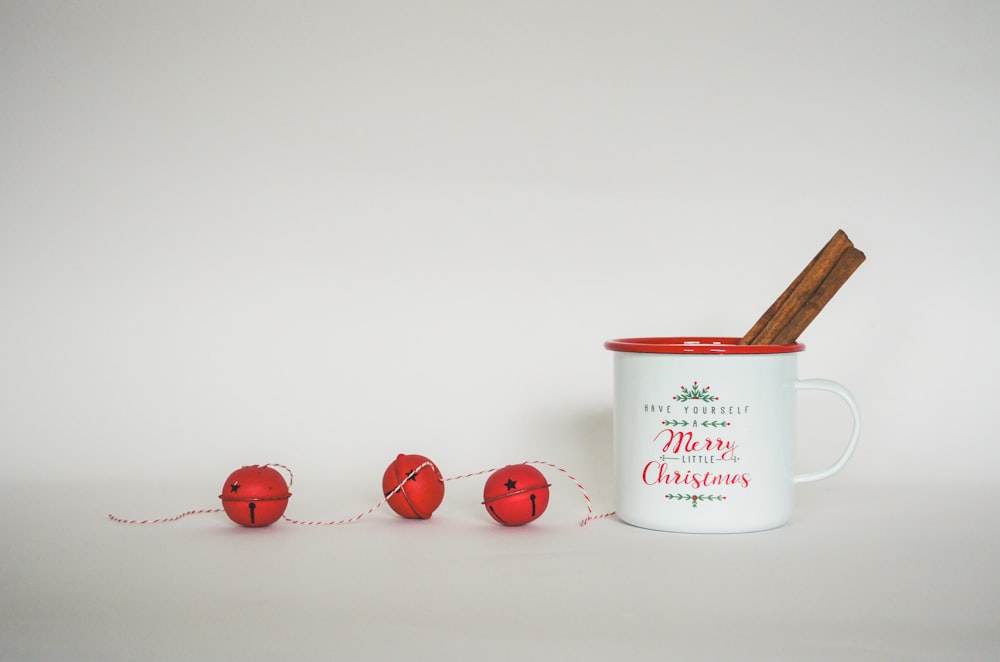 una tazza con un bastoncino accanto a tre palline rosse