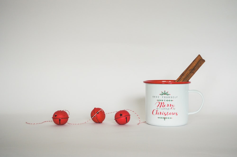 a mug with a stick in it next to three red balls