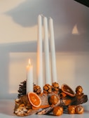 Elegant arrangement of several domovsviečka candles in white and cream tones with gold accents.