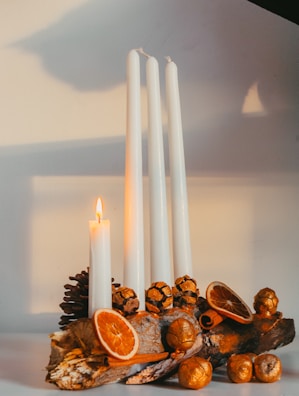 Elegant arrangement of several domovsviečka candles in white and cream tones with gold accents.