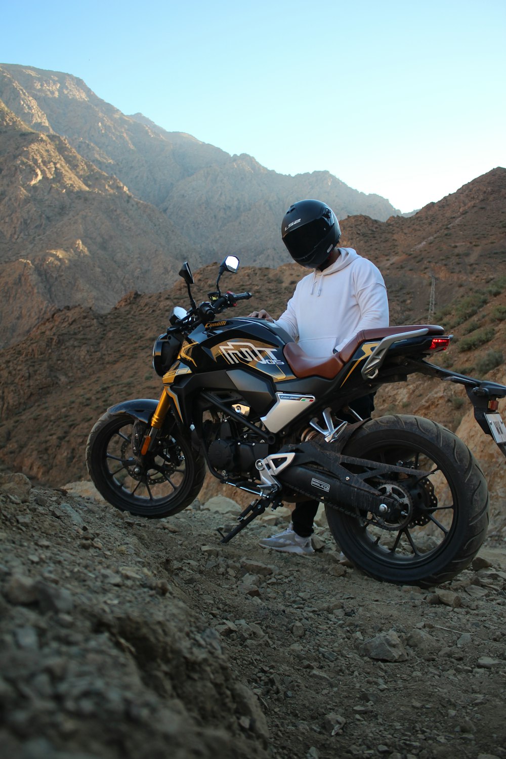 a man sitting on a motorcycle on top of a mountain