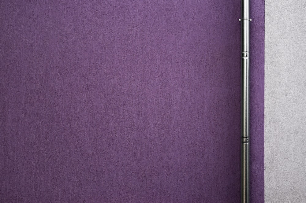 a purple wall with a metal pole on top of it