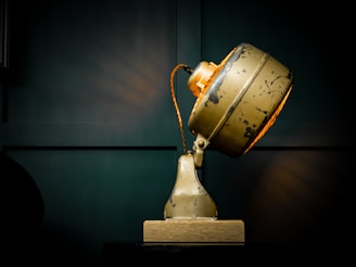 A sleek vintage lamp with a glowing filament bulb casting soft shadows on a minimalist wooden desk.