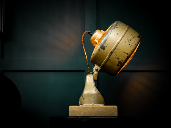 A quirky, retro-style desk lamp casting a warm glow over a cluttered workspace.