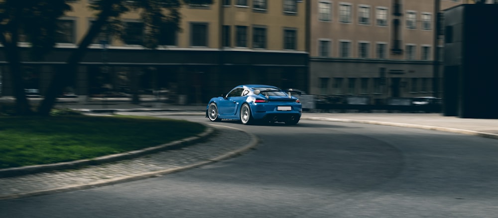 a blue car driving down a street next to tall buildings