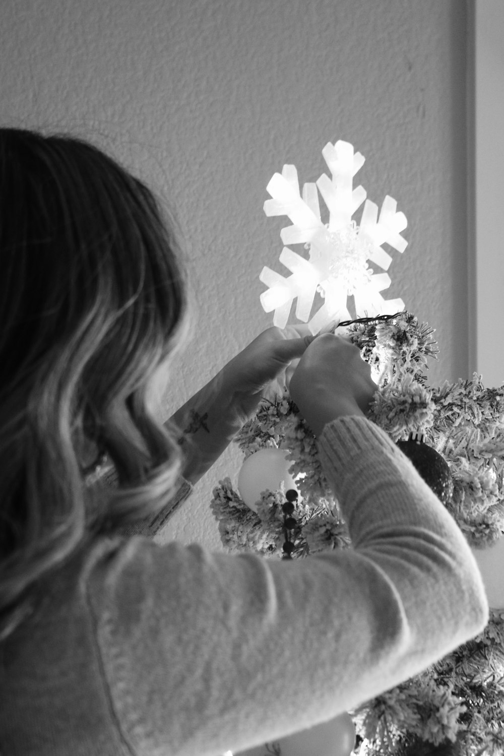a woman decorating a christmas tree with snowflakes