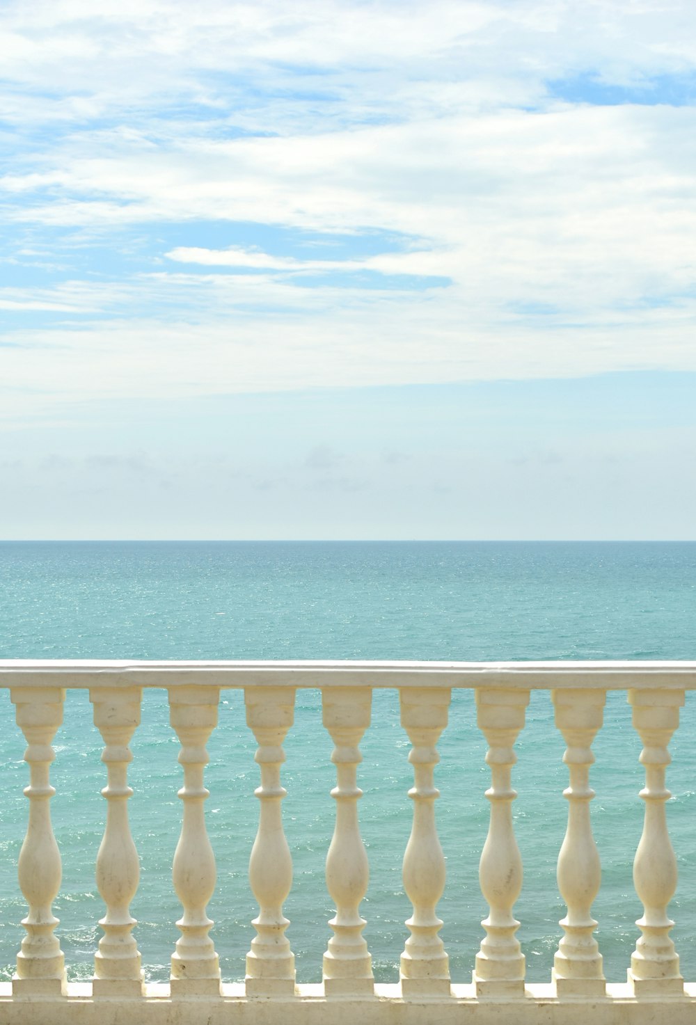 a woman standing on a balcony next to the ocean