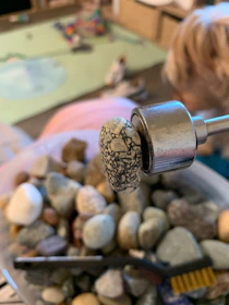Artisan carefully selecting vibrant Mexican stones surrounded by natural fibers and tools.