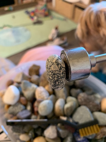 Artisan carefully selecting rare ornamental stones in a sunlit workshop.